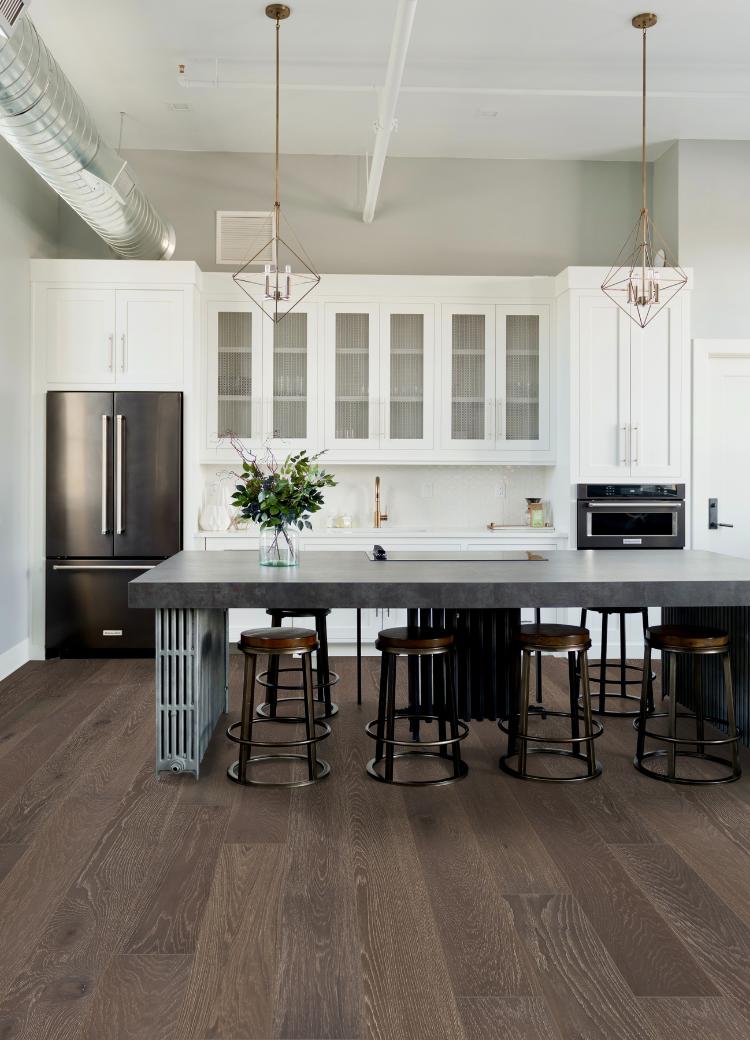 hardwood flooring in kitchen with white cabinets and stone kitchen island with mixed metal decor.